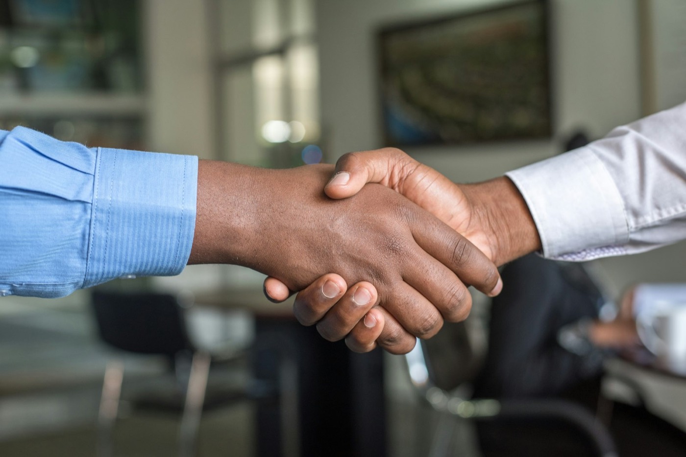Two people shaking hands across a table after reaching an agreement