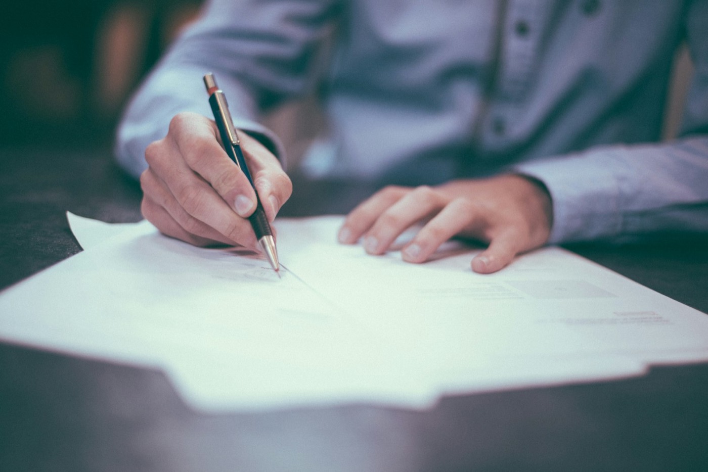 A person signing a document with a fountain pen